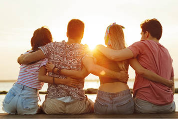 Back view photo of group of four friends loving couples walking outdoors on the beach.