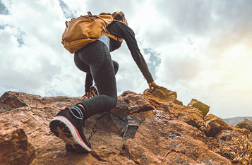 Success woman hiker hiking on sunrise mountain peak - Young woman with backpack rise to the mountain top. Discovery Travel Destination Concept